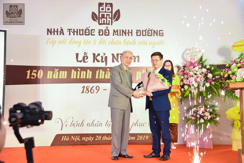 Lương y Đỗ Minh Tuấn - Đại diện nhà thuốc Đỗ Minh Đường nhận hoa từ ông Nguyễn Đức Đoàn - Chủ tịch Hội nam y Việt Nam